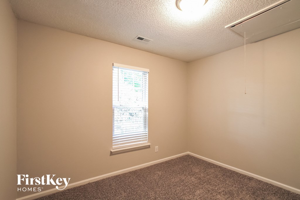 the upstairs bedroom has a large window and carpeted flooring
