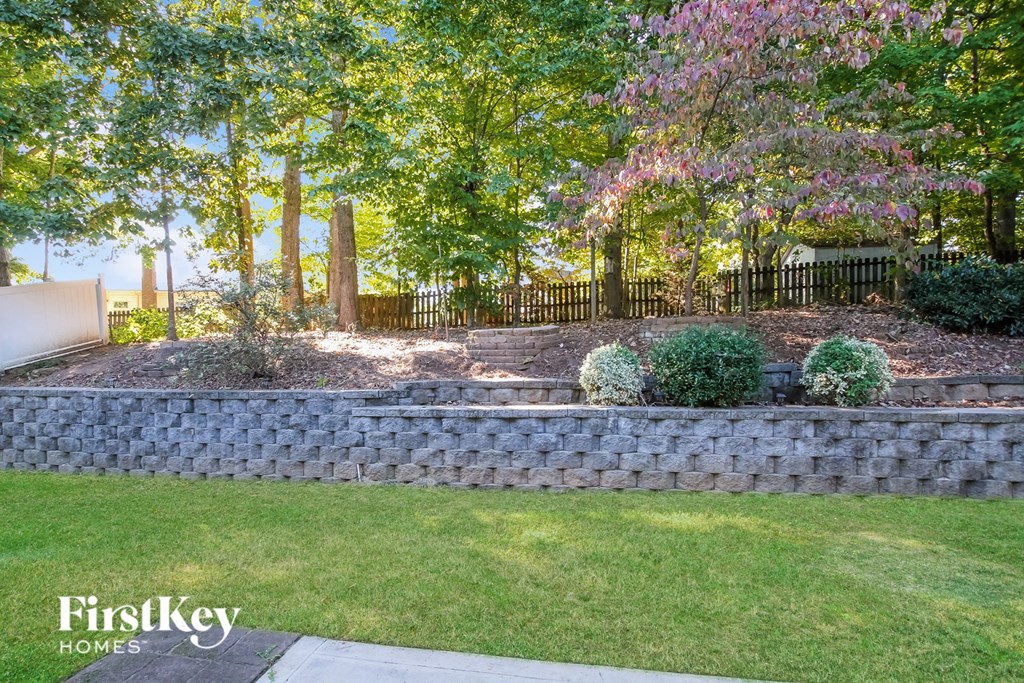 a retaining wall in a backyard with trees and grass