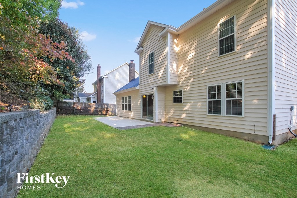 a backyard with a white house and a green lawn