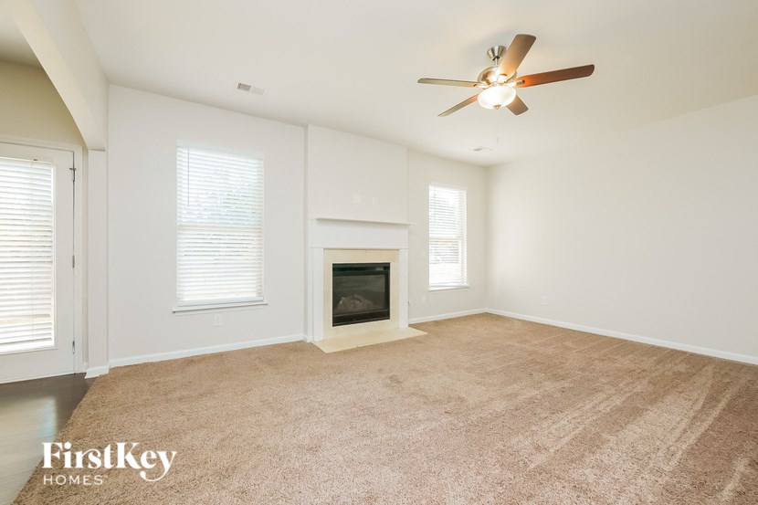 A spacious living room with a fireplace and a ceiling fan.