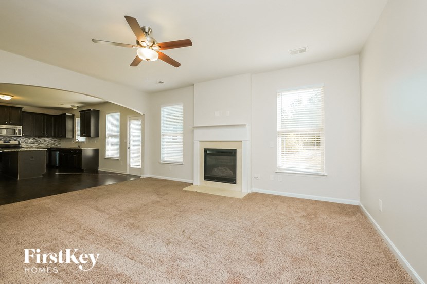 A spacious living room with a fireplace and a ceiling fan.