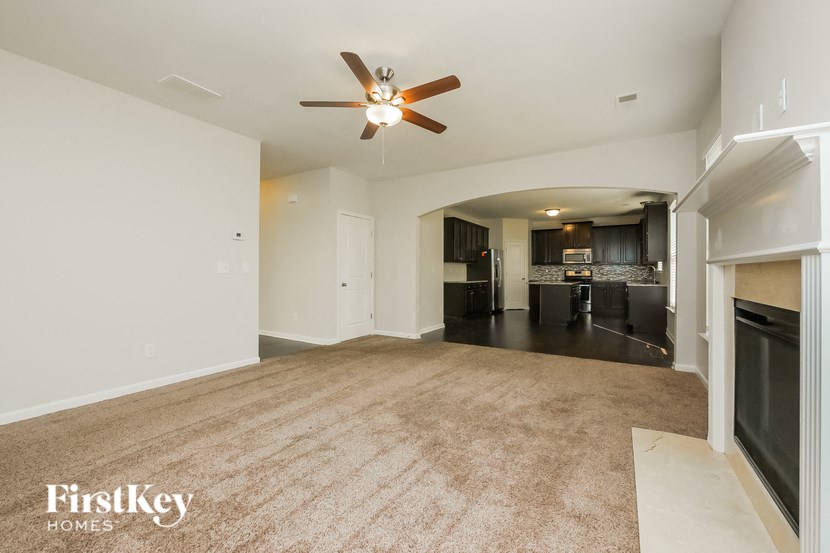 A spacious living room with a fireplace and a ceiling fan.