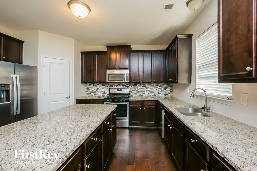 A kitchen with dark wood cabinets and granite countertops.