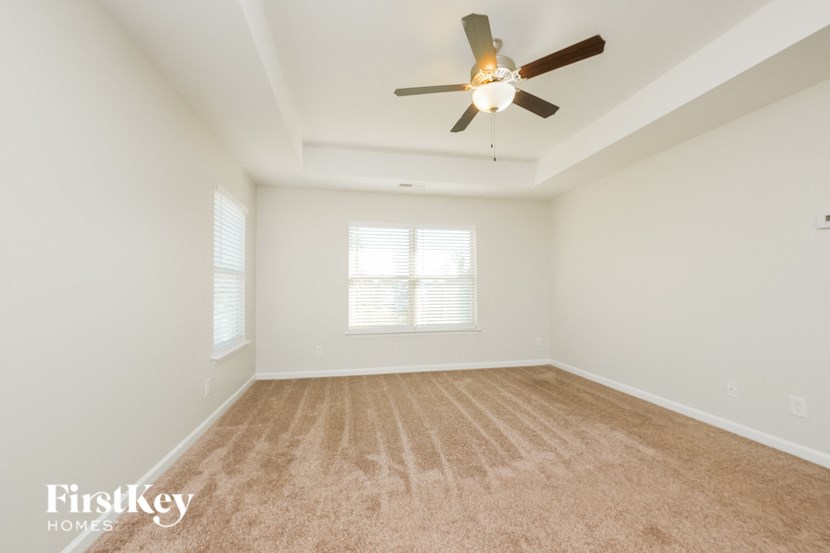 A room with a ceiling fan and carpeted floor.