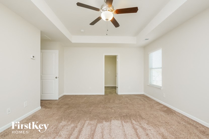 A room with a ceiling fan and carpeted floor.
