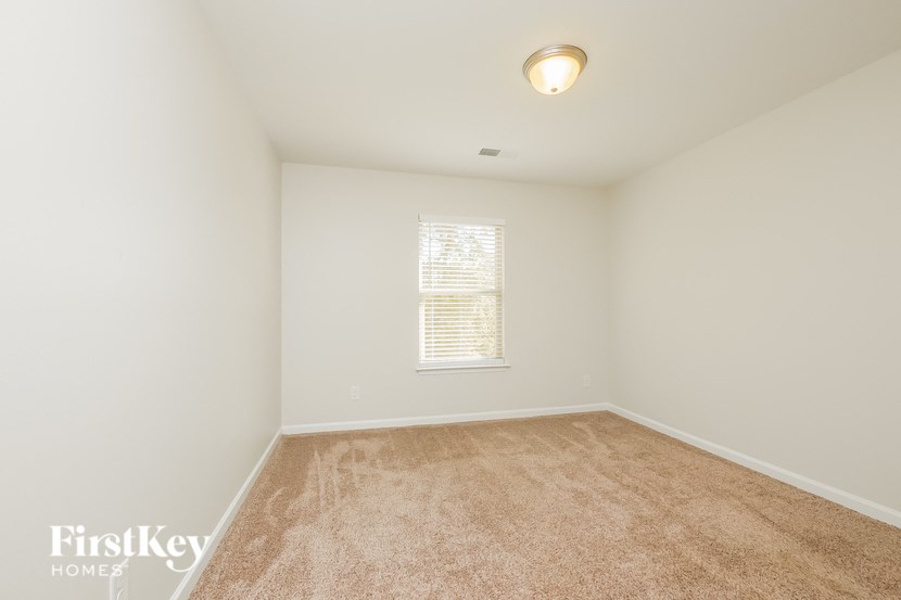 A carpeted room with a window and a light on the ceiling.