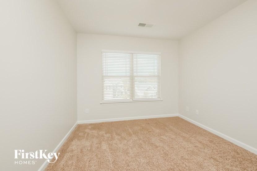 A room with a carpeted floor and a window with blinds.