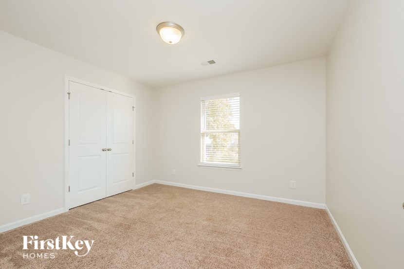 A room with a carpeted floor and a window with blinds.