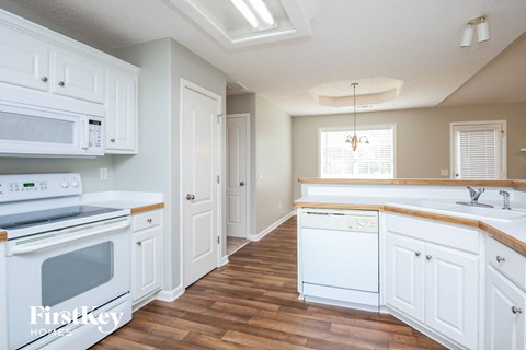 A kitchen with white cabinets and a wooden floor.