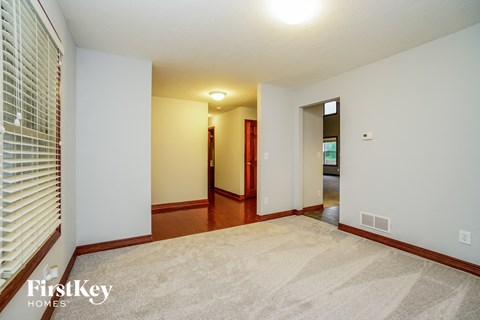 the living room and dining room of a house with white walls and wood flooring