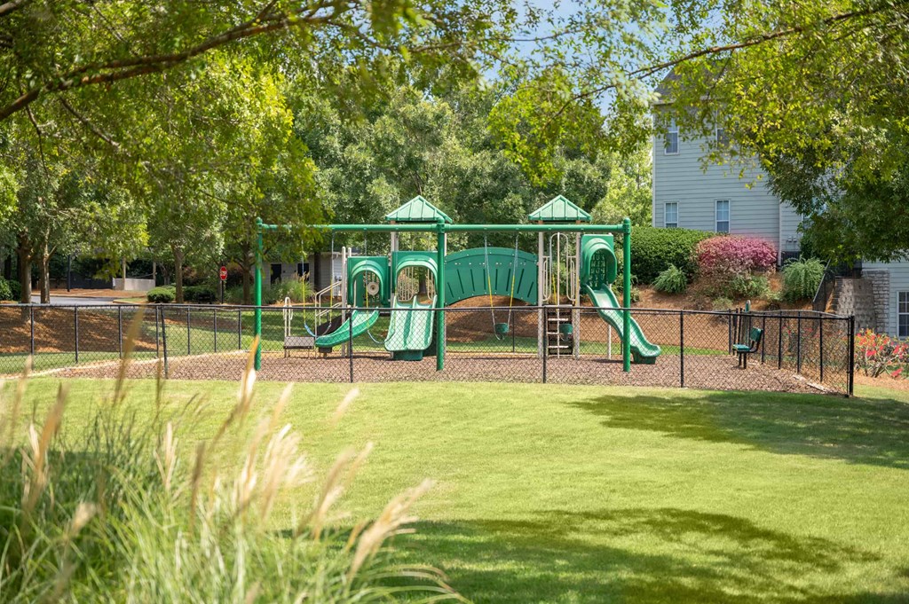 A playground with a green slide and a green canopy.