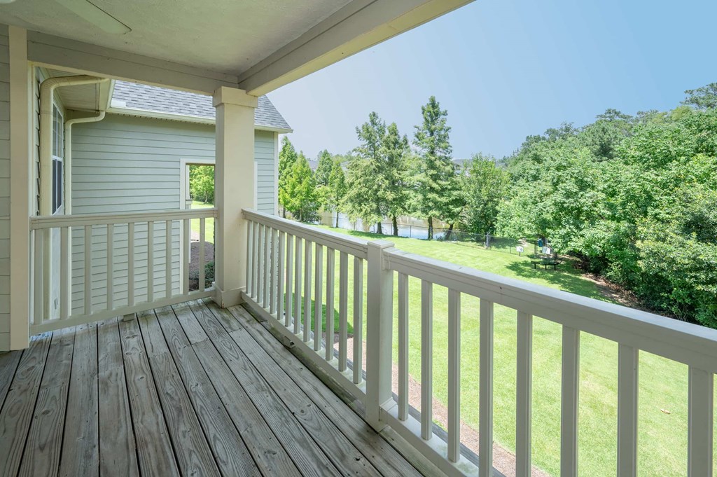 A white porch with a view of a green lawn and trees.