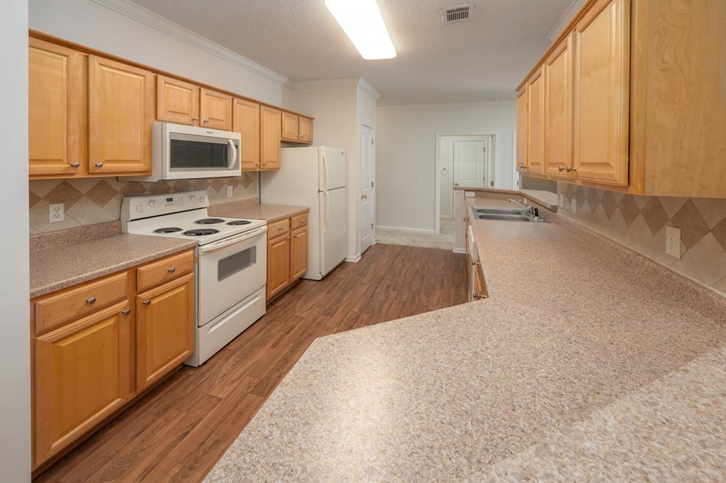 A kitchen with wooden cabinets and a white stove top oven.