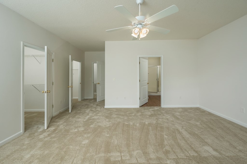 A room with a ceiling fan and carpeted floor.