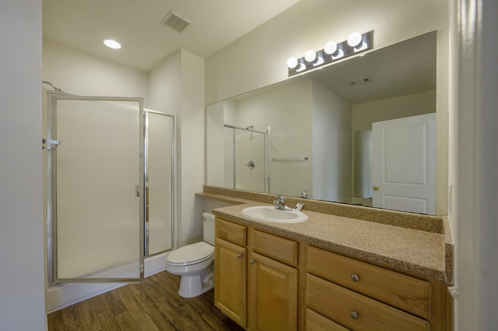 A bathroom with a toilet, sink, and mirror.