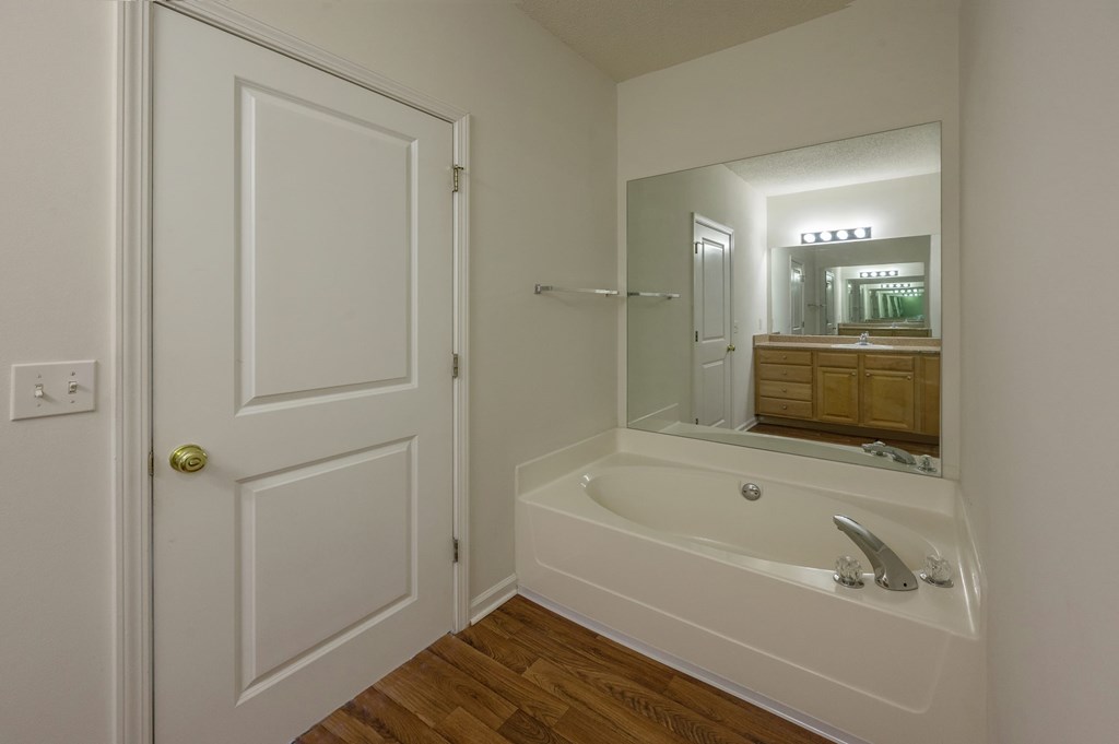 A white bathroom with a tub and a mirror.