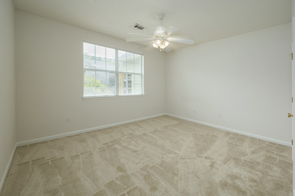 A room with a ceiling fan and a window.