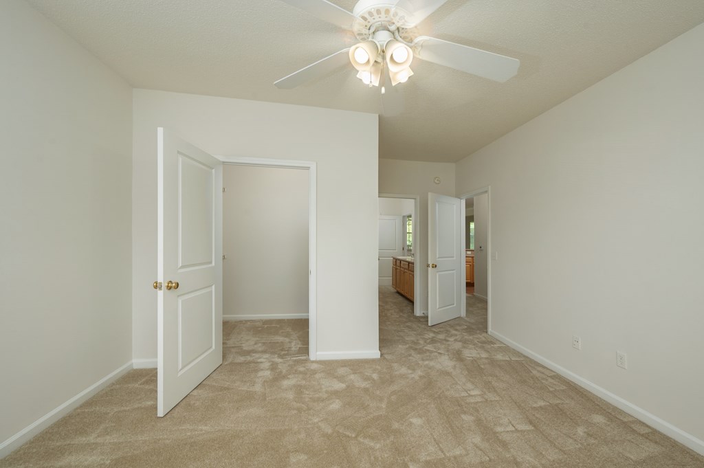 A room with a ceiling fan and carpeted floor.