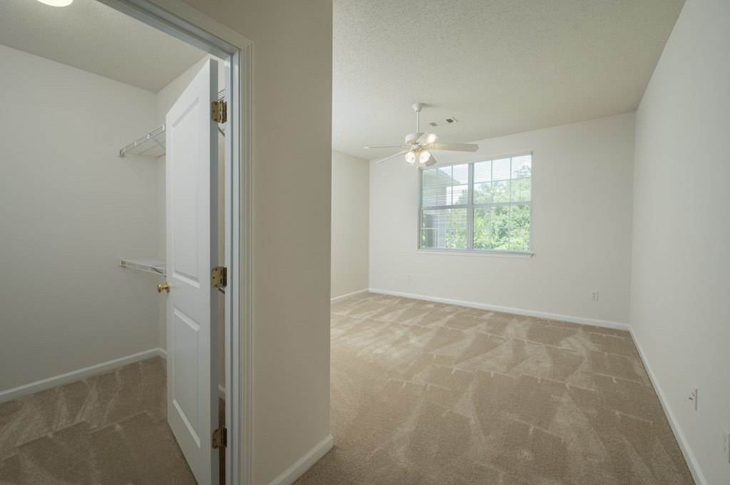A room with a carpeted floor and a door leading to another room.