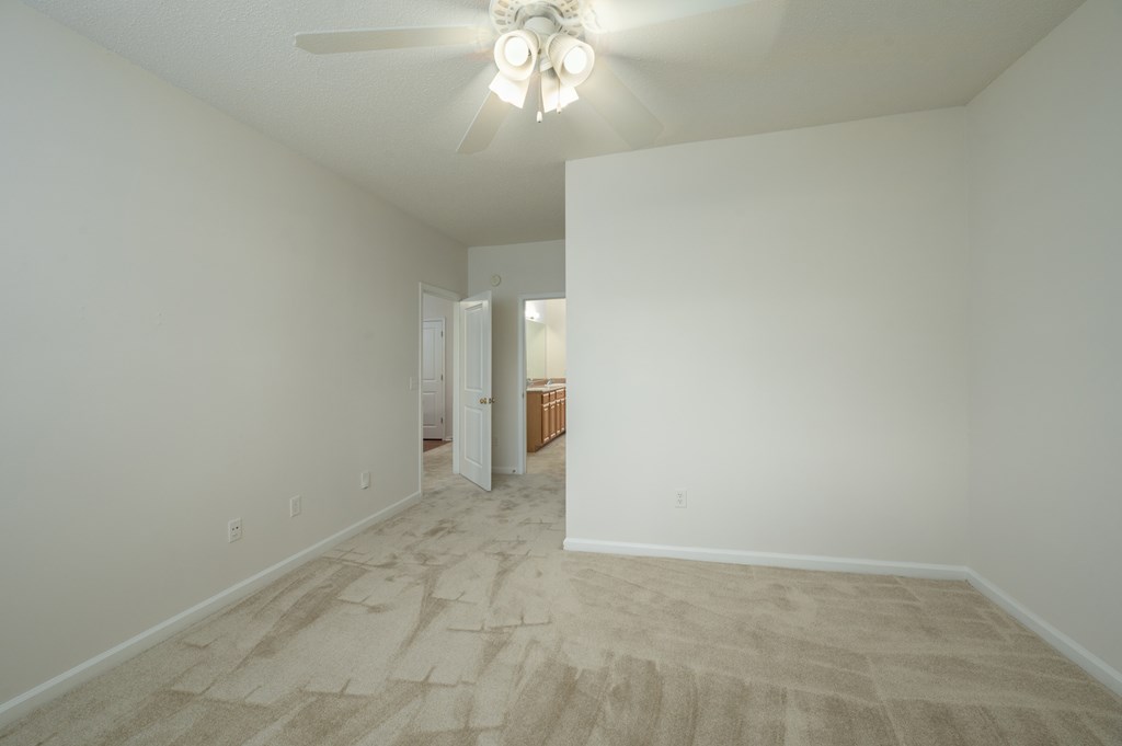 A room with a ceiling fan and carpeted floor.