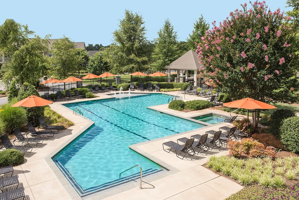 A large swimming pool surrounded by lawn chairs and umbrellas.