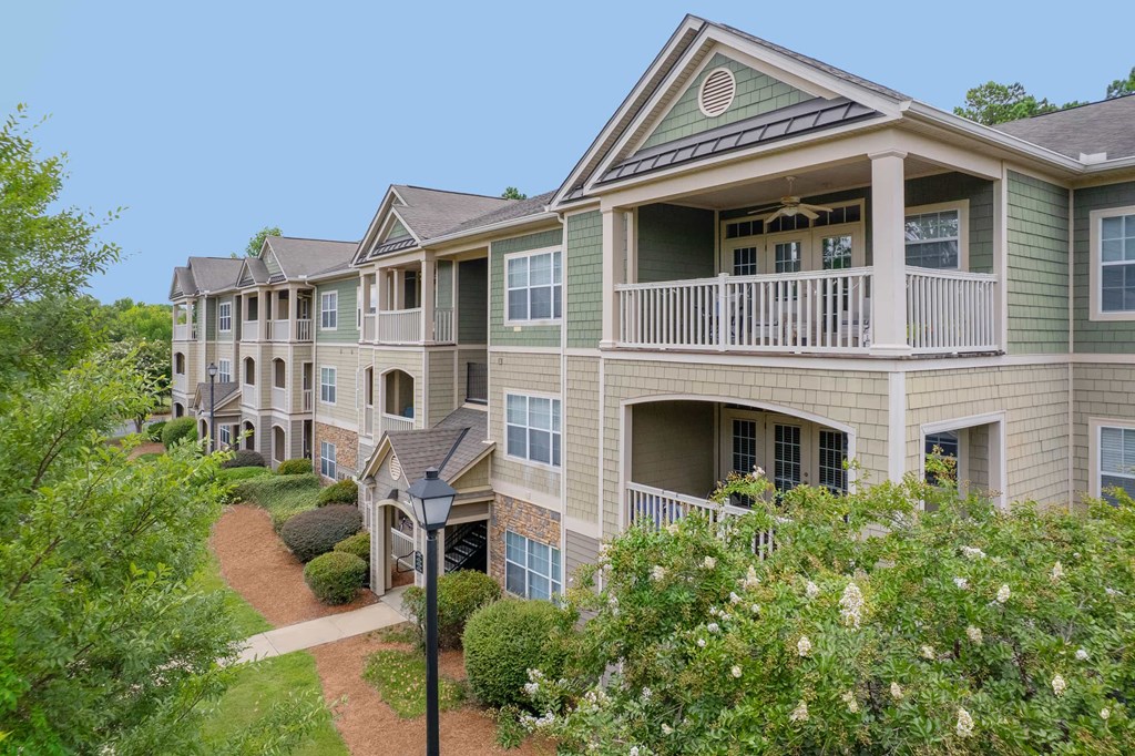 A row of houses with green trees in front.