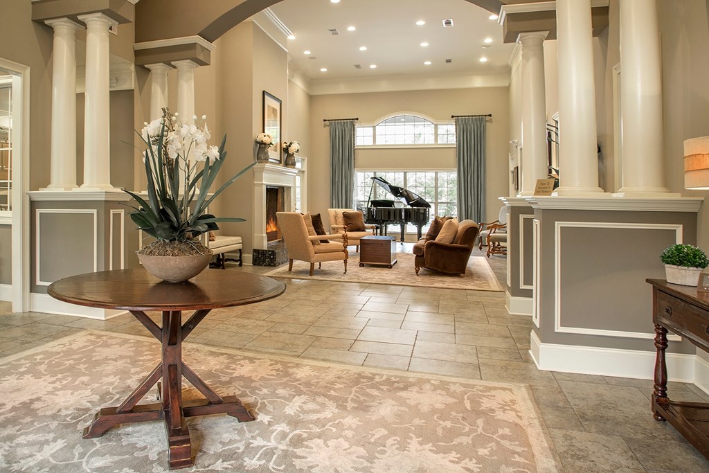 A large, elegant room with a piano and a vase of flowers on a table.