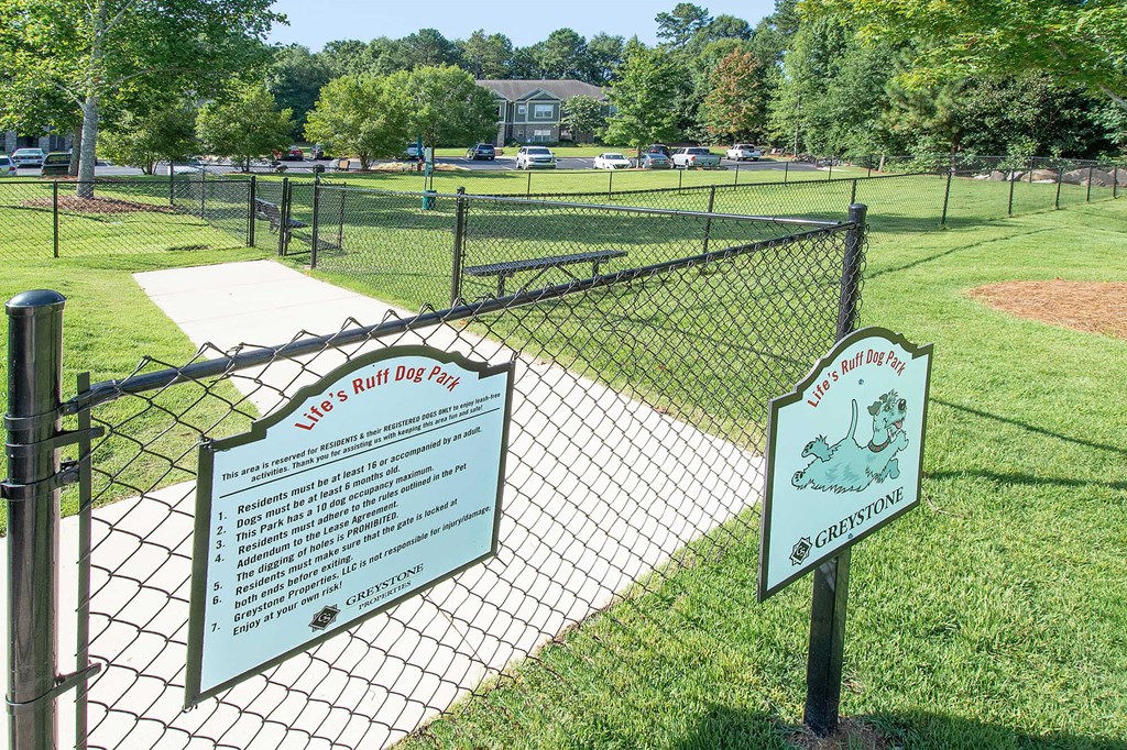 A sign at a dog park provides rules and regulations for visitors.