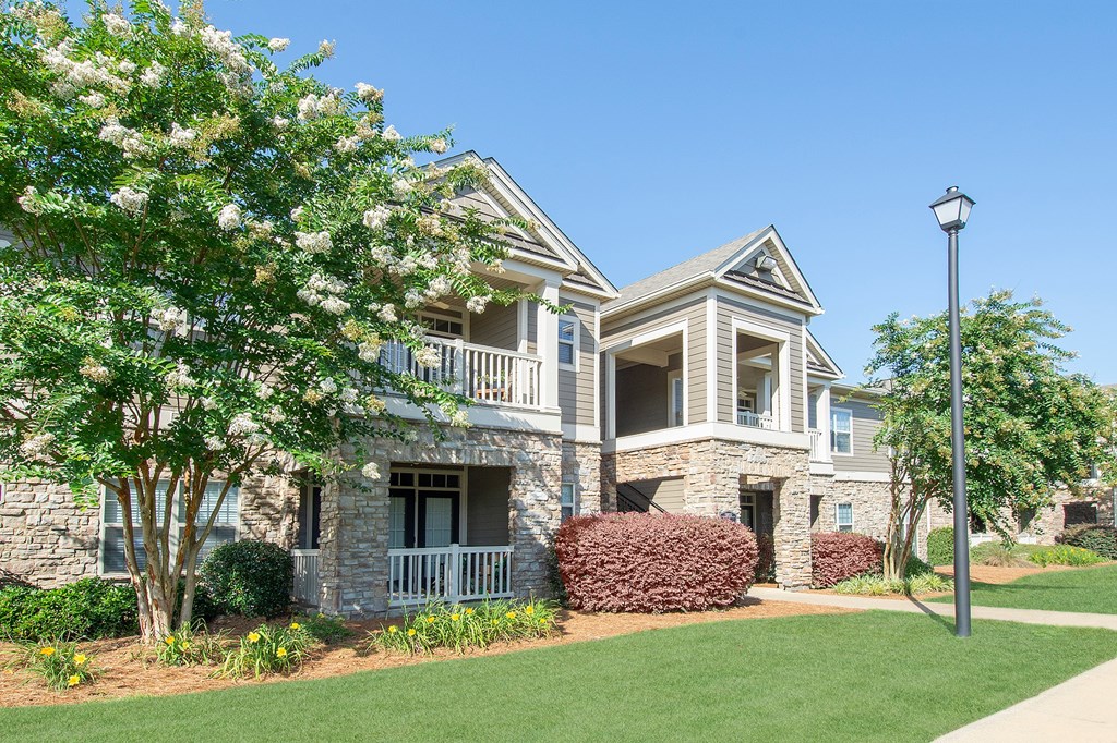 A house with a white picket fence and a tree in front.