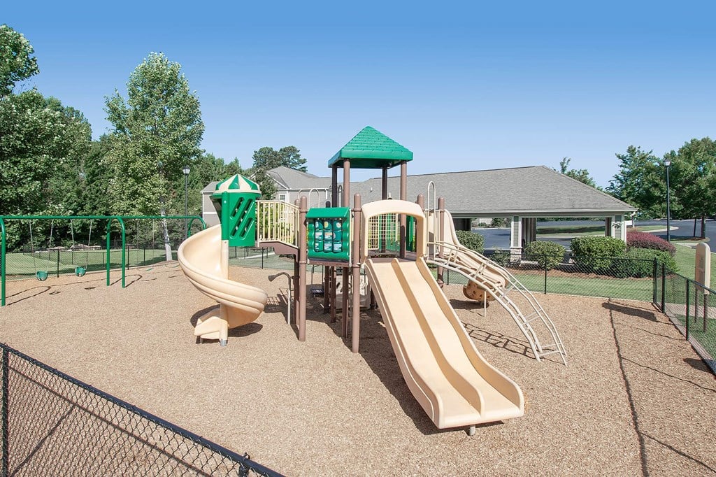 A playground with a green roofed structure and a yellow slide.