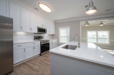 A modern kitchen with white cabinets and a stainless steel refrigerator.