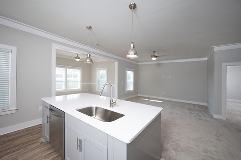 A kitchen with a white countertop and a stainless steel sink.