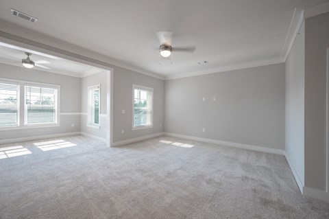 A spacious room with a carpeted floor and a ceiling fan.