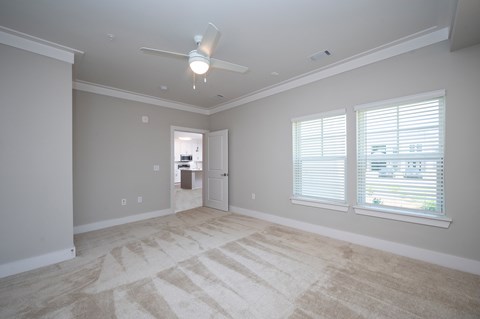 A room with a carpeted floor and a ceiling fan.