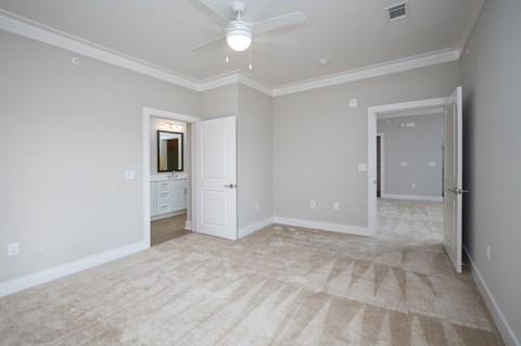 A room with a carpeted floor and a ceiling fan.