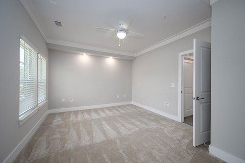 A room with a carpeted floor and a ceiling fan.