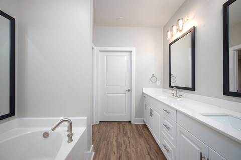 A white bathroom with a tub, sink, and mirror.