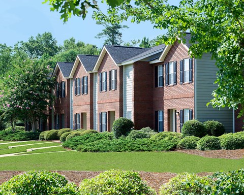 A red brick house with a green lawn in front.