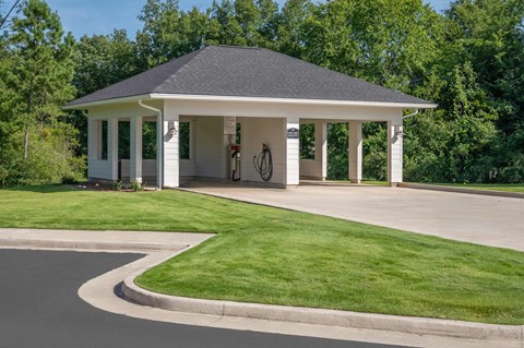 A small white building with a black roof and a bicycle hanging on the wall.