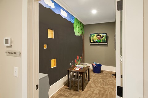 A room with a table and chairs and a TV mounted on the wall.