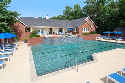 A pool with a diving board and a house in the background.