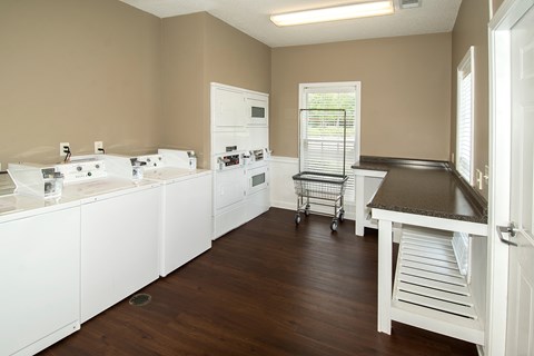 A kitchen with white appliances and wooden floors.