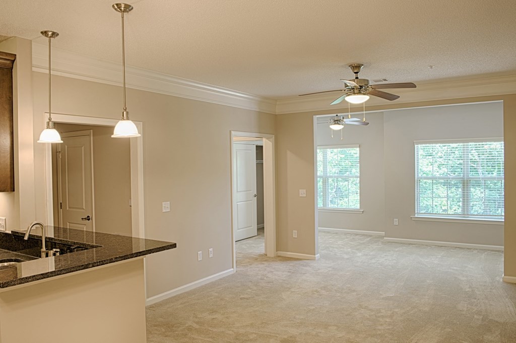 A spacious kitchen with a sink, a ceiling fan, and a window.