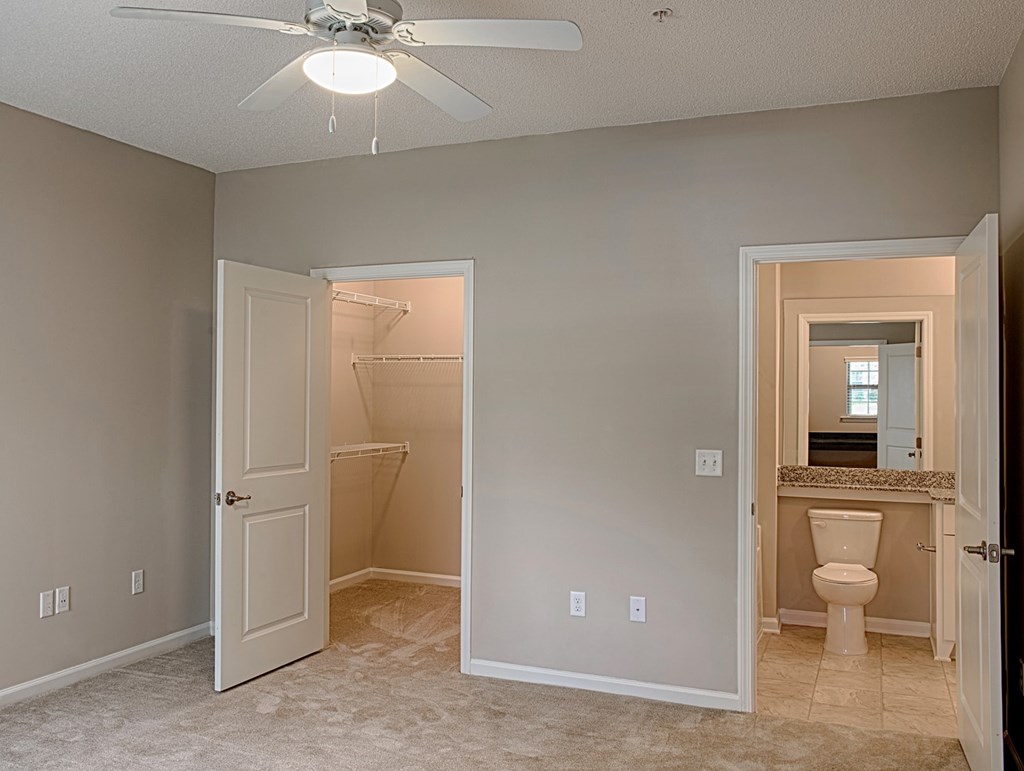 A room with a ceiling fan and a toilet in the bathroom.