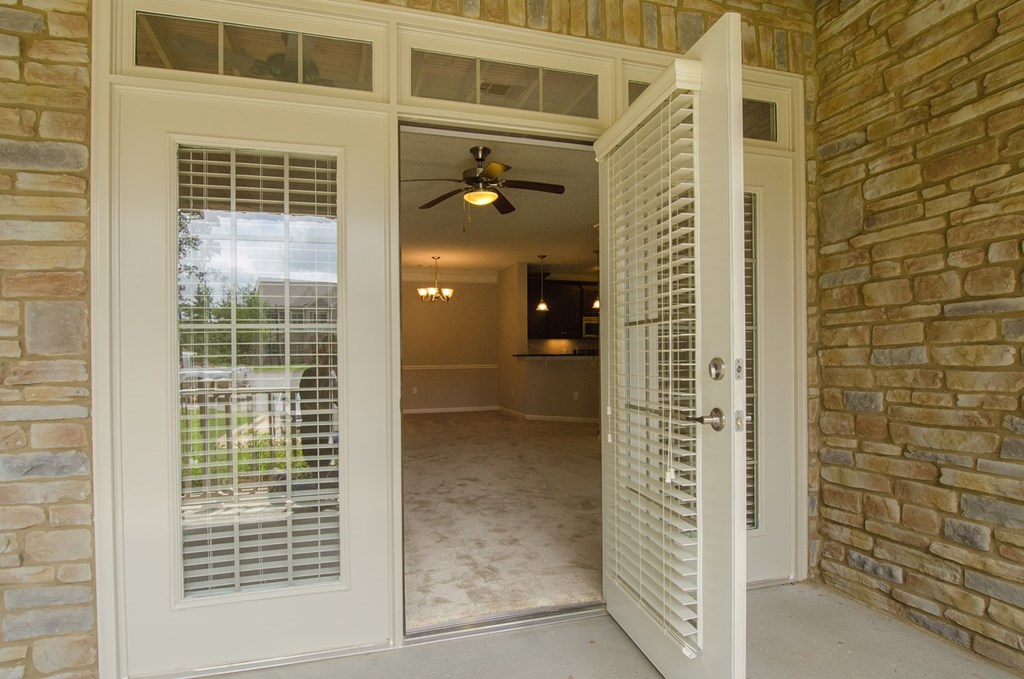 A white door with a glass window is open to a room with a ceiling fan.