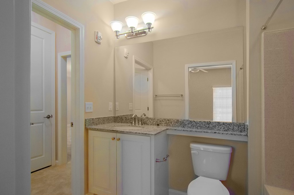 A bathroom with a toilet, sink, and mirror.
