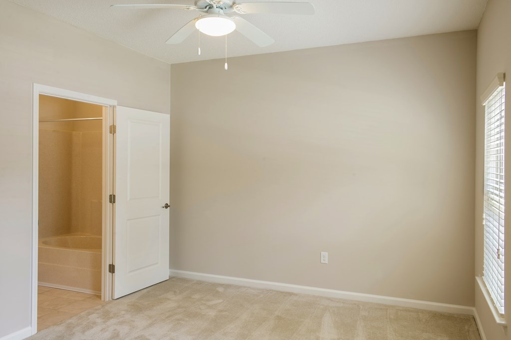 A room with a ceiling fan and a door leading to another room.