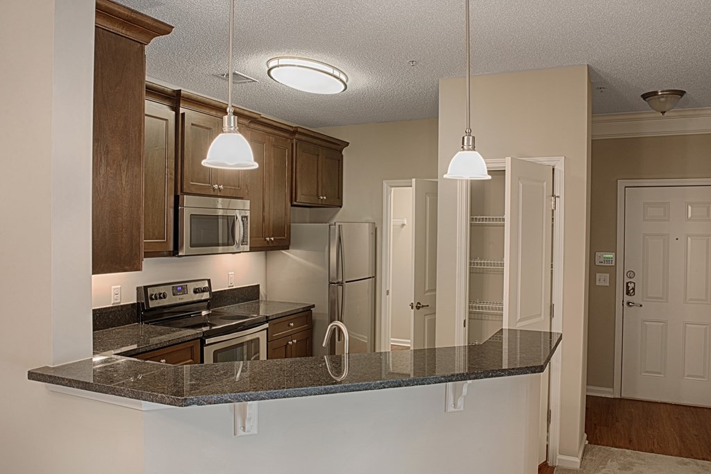 A kitchen with a granite countertop and wooden cabinets.