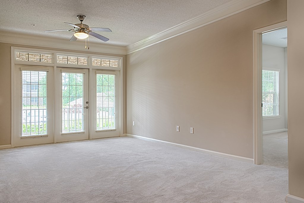 A room with a ceiling fan and sliding glass doors.