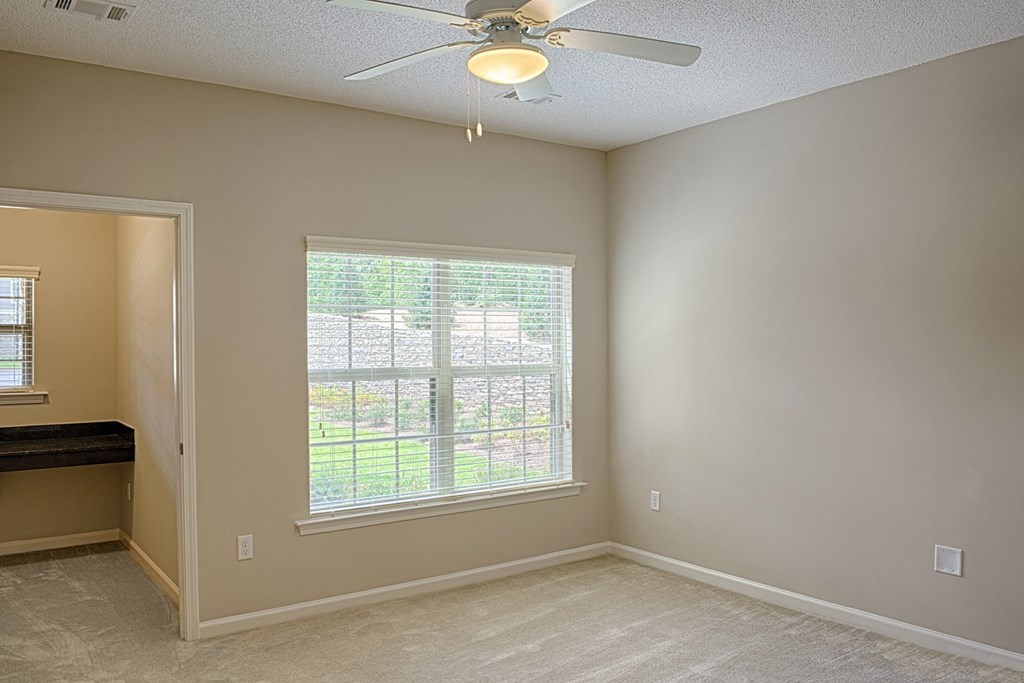 A room with a ceiling fan and a window with blinds.